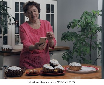 An Elderly Woman On The Easter Holiday Takes Homemade Cakes With Raisins And Cream, And Colored Eggs On Her Phone.