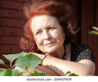 Elderly Woman On Porch Of Country House On Autumn Day.