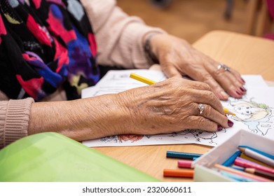 Elderly woman painting color on her drawing. Hobby at nursing home. High quality photo - Powered by Shutterstock