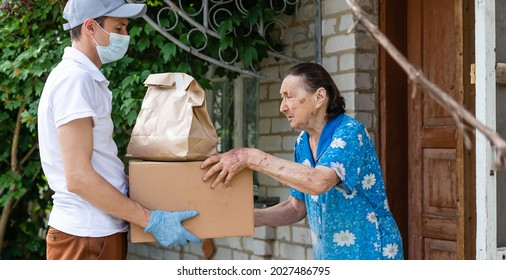 Elderly Woman Paying Courier Of Food Delivery Company For Order Via Terminal. Concept Of Epidemic