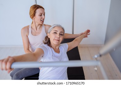 Elderly Woman Pilates Reformer Cadillac Exercise Workout With Beautyful Female Personal Trainer In Pilates Studio.