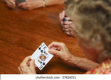 Elderly Woman Playing Cards. Shallow Depth Of Field. Focus On Hands Holding Cards. Room For Text.