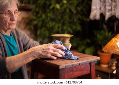 Elderly Woman Polishing A Brass Candle Holder