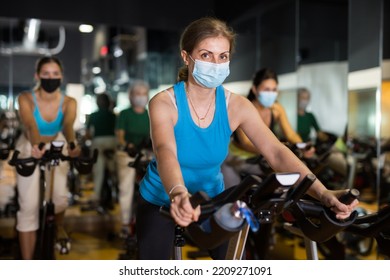 Elderly Woman In Protective Fase Mask Warming Up On Bikes In Spin Class At Gym