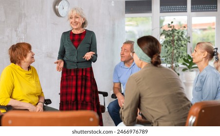 Elderly woman psychologist attentively listens to the stories of adults in group therapy - Powered by Shutterstock