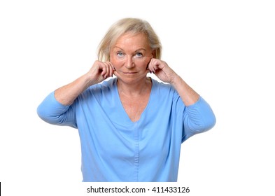Elderly woman pulling at the skin on her jowls or cheeks pinching it between her fingers showing the ageing process in a beauty concept, upper body isolated on white