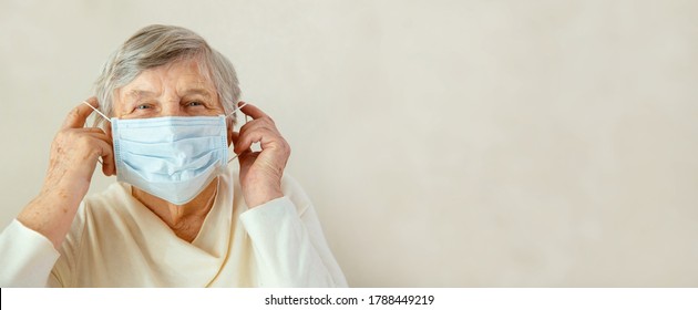 An Elderly Woman Puts A Medical Mask On Her Face. Woman With Medical Mask Worries About Coronavirus