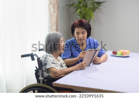 Elderly woman reading aloud a book for dementia therapy with caregiver.