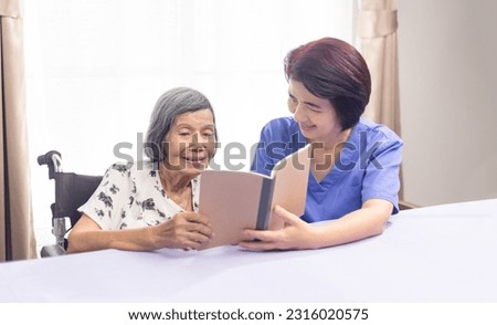 Elderly woman reading aloud a book for dementia therapy with caregiver.