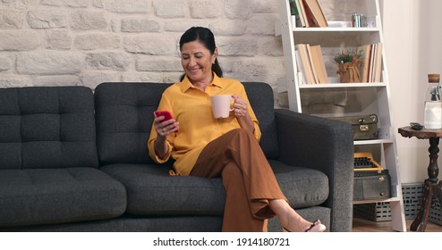 Elderly Woman Is Reading News On The Phone And Drinking Coffee.