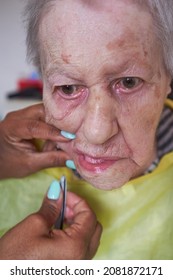 Elderly Woman Receiving Facial Hair Removal From African American Caregiver
