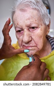 Elderly Woman Receiving Facial Hair Removal From African American Caregiver
