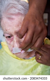 Elderly Woman Receiving Facial Hair Removal From African American Caregiver
