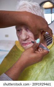 Elderly Woman Receiving Facial Hair Removal From African American Caregiver
