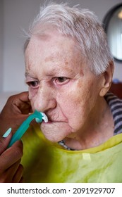 Elderly Woman Receiving Facial Hair Removal From African American Caregiver
