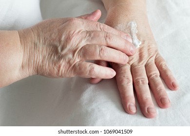 Elderly Woman Rubbing Hand Cream, White Background, Close-up