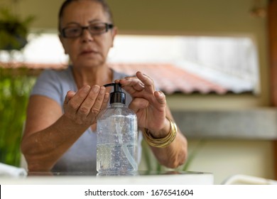 Elderly woman sanitizing her hands with alcohol gel - Powered by Shutterstock