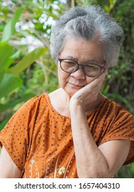 Elderly woman with short white hair toothache standing in garden. Asian senior woman unhealthy and have negative thoughts on life make her unhappy. Concept of health care and mental