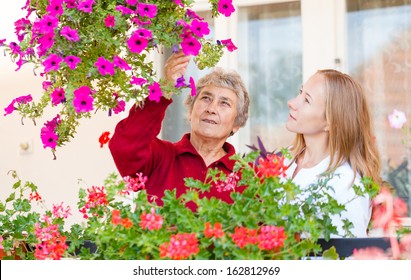 Elderly Woman Shows Her Flowers To Her Assistant