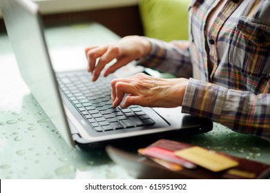 The elderly woman sick with rheumatoid arthritis using internet banking it home. Modern technologies facilitate life to elderly, sick, lonely people. New opportunities, help.