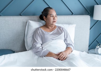 Elderly Woman Sits Lonely In Her Bed Waiting To See Her Grandchildren In Her Bedroom At Home.