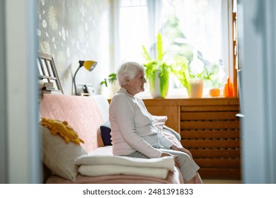 Elderly woman sitting alone on a bed in nursing home 
 - Powered by Shutterstock