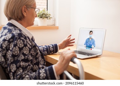 Elderly Woman Sitting By Desk At Home,leaning Onto Upright Walker,consulting With E-doctor Over Online Computer Call,young Female NHS GP Medical Healthcare Specialist Giving Advice To Senior Patient