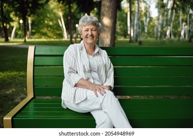 An elderly woman sitting on bench in summer park