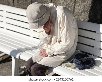 Elderly woman sitting on a bench and crying - Powered by Shutterstock