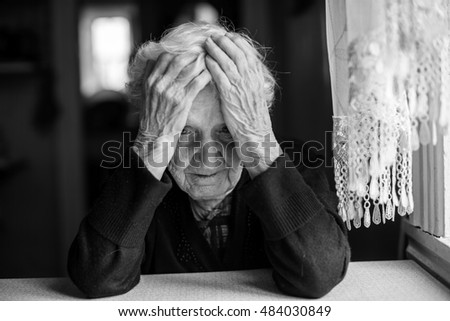 An elderly woman sitting at the table in a depressed state, black and white photo.