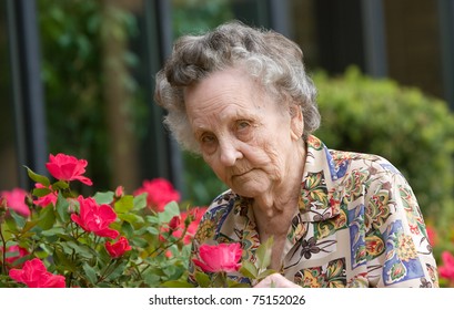 Elderly Woman Smelling Flowers Outside During Spring
