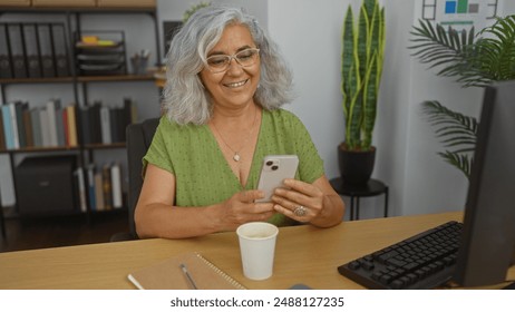 Elderly, woman, smiling, using, smartphone, in, modern, office, environment, with, plants, and, notebooks - Powered by Shutterstock