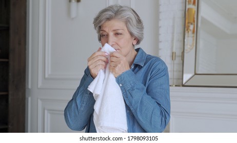 An Elderly Woman Sniffs A Fresh Towel At Home