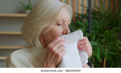 An Elderly Woman Sniffs A Fresh Towel At Home