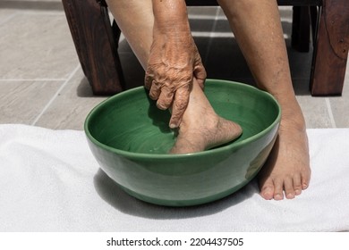Elderly woman soaking feet with warm salt water at home.