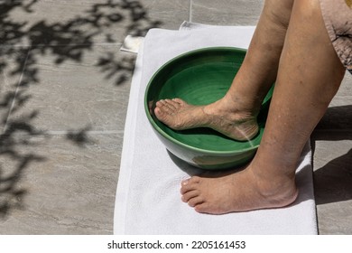 Elderly woman soaking feet with warm salt water at home. - Powered by Shutterstock