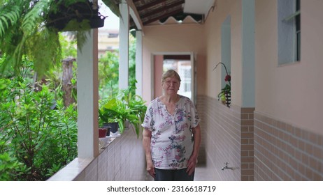 Elderly woman standing at home in casua South American Residence backyard. Senior female person in 70s, domestic authentic real people