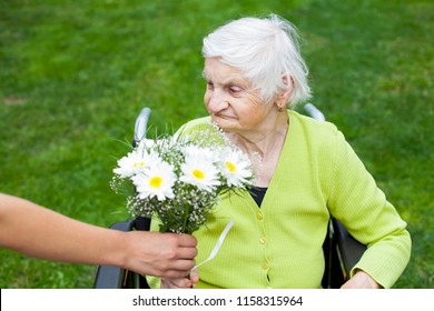 Elderly Woman Suffering From Dementia Disease Receiving Flowers For Her Birthday