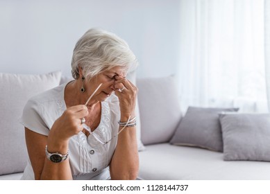 Elderly woman suffering from headache at home. Close up aged woman with headache. Health care, pain, stress, age and people concept 