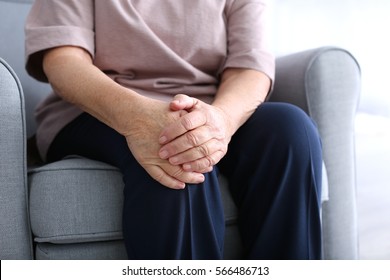 Elderly Woman Suffering From Pain In Knee At Home, Closeup