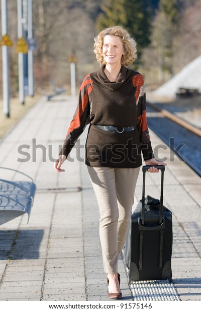 elderly woman with a suitcase while traveling at\
the station /older lady on the\
road