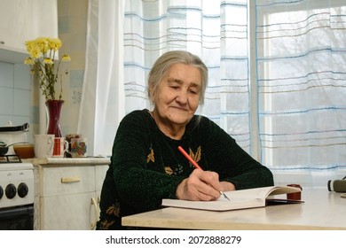 An Elderly Woman At The Table Fills A Day Planner With A Vintage Pen