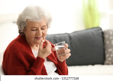 Elderly Woman Taking Pill At Home