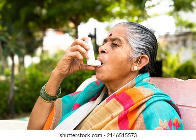 elderly woman using asthma inhaler while sitting at park due to allergy - concept showing effects of pollution, illnes and disease - Powered by Shutterstock