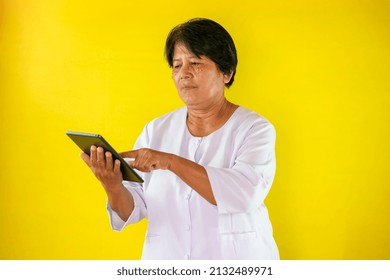 Elderly Woman Using Ipad Isolated On Yellow Background