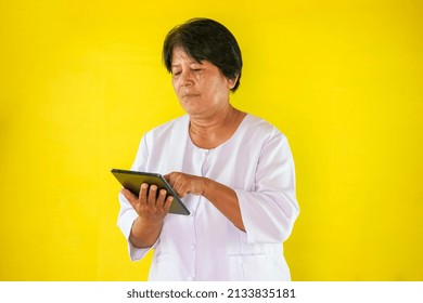 Elderly Woman Using Ipad Isolated On Yellow Background