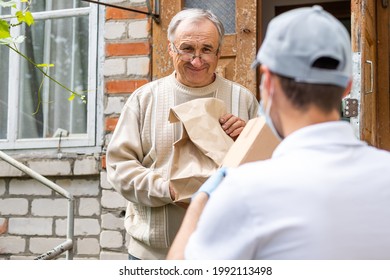 An Elderly Woman Using A Walker Receives Meals From A Man Working With A Benevolent Group Delivering Food To Those Who Are At High Risk Because Of The Coronavirus COVID19.