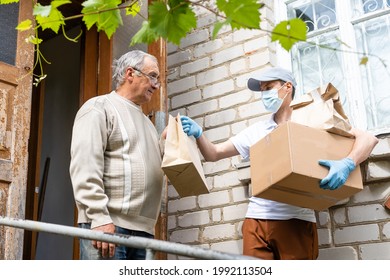 An Elderly Woman Using A Walker Receives Meals From A Man Working With A Benevolent Group Delivering Food To Those Who Are At High Risk Because Of The Coronavirus COVID19.