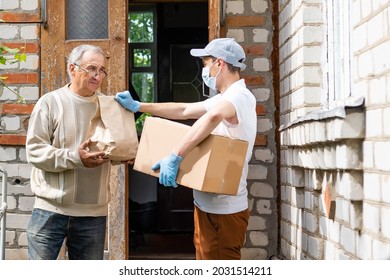 An elderly woman using a walker receives meals from a man working with a benevolent group delivering food to those who are at high risk because of the coronavirus COVID19. - Shutterstock ID 2031514211