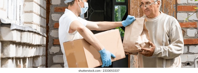 An elderly woman using a walker receives meals from a man working with a benevolent group delivering food to those who are at high risk because of the coronavirus COVID19. - Powered by Shutterstock